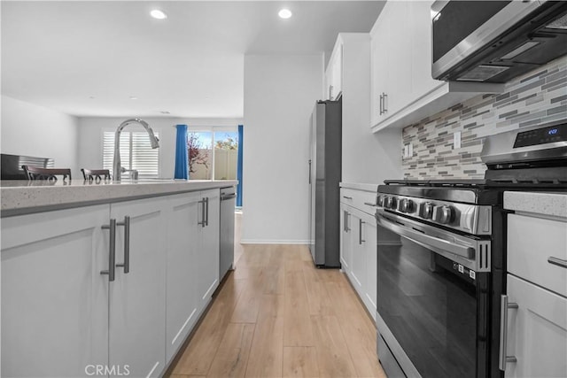 kitchen with stainless steel appliances, light hardwood / wood-style flooring, and white cabinetry