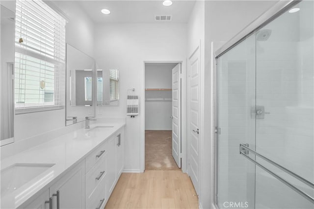 bathroom featuring vanity, hardwood / wood-style flooring, and a shower with door