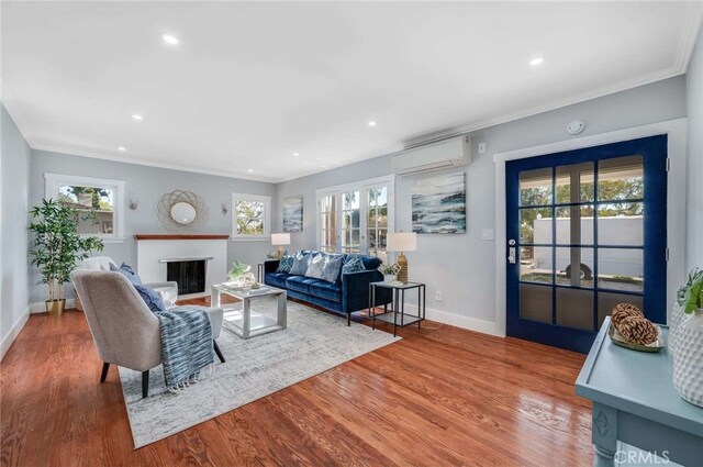 living room featuring plenty of natural light, wood-type flooring, a wall mounted air conditioner, and ornamental molding