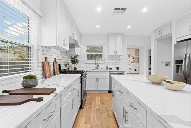 kitchen featuring light stone countertops, sink, stainless steel appliances, and white cabinetry