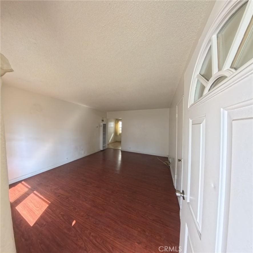 unfurnished room featuring a textured ceiling and dark hardwood / wood-style flooring