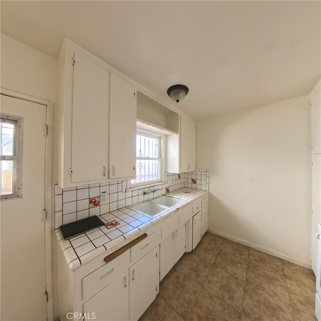 kitchen with tile counters, sink, tasteful backsplash, tile patterned flooring, and white cabinets