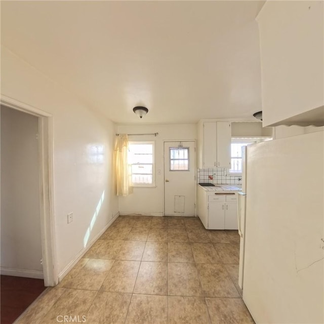 kitchen with white cabinets, decorative backsplash, white fridge, and light tile patterned flooring