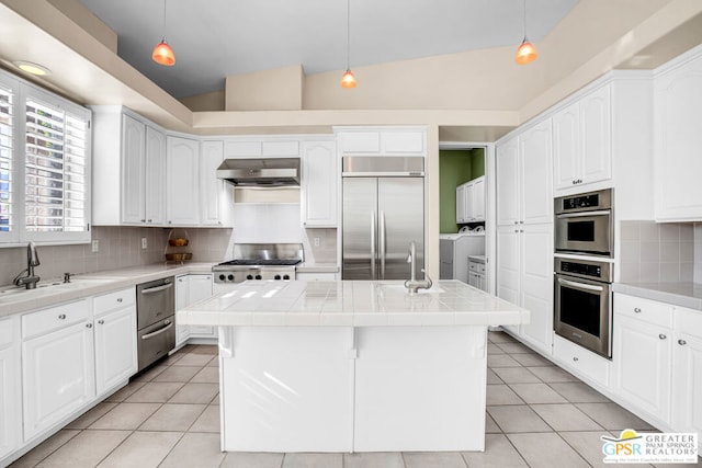 kitchen with pendant lighting, a center island, vaulted ceiling, and appliances with stainless steel finishes