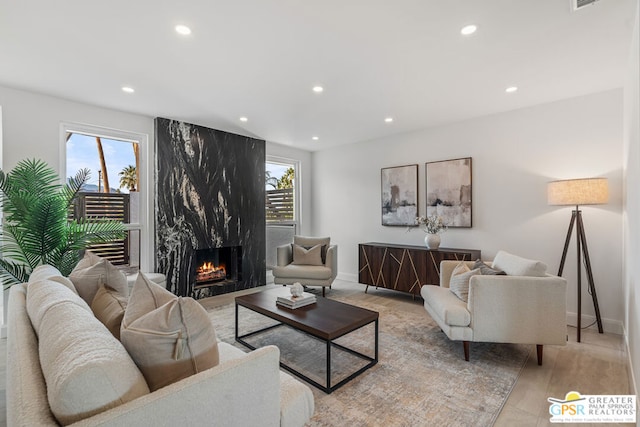 living room featuring a high end fireplace and light hardwood / wood-style flooring