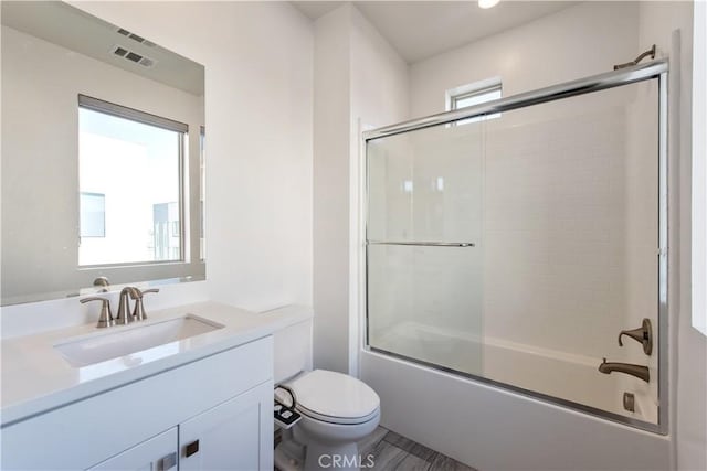 full bathroom with combined bath / shower with glass door, vanity, and toilet