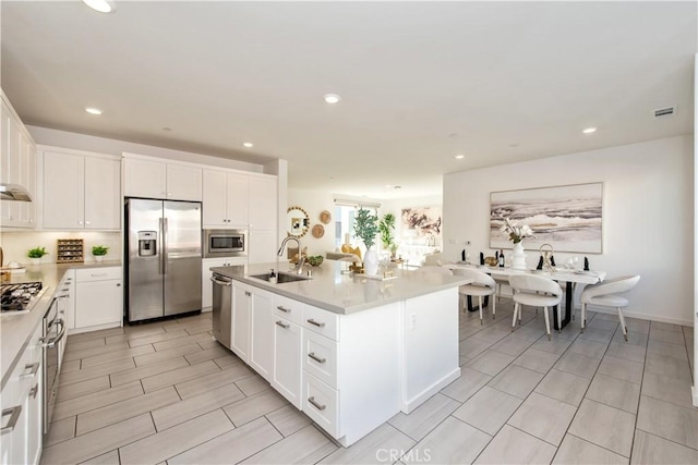 kitchen featuring appliances with stainless steel finishes, an island with sink, white cabinets, and sink