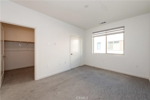 unfurnished bedroom with a spacious closet, a closet, and carpet floors