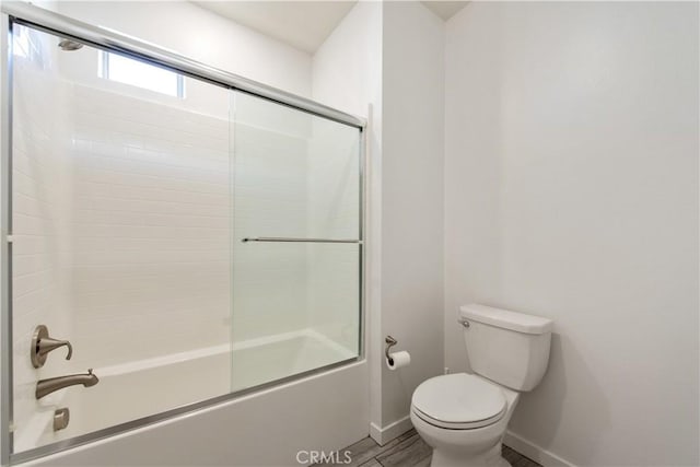 bathroom with toilet and bath / shower combo with glass door