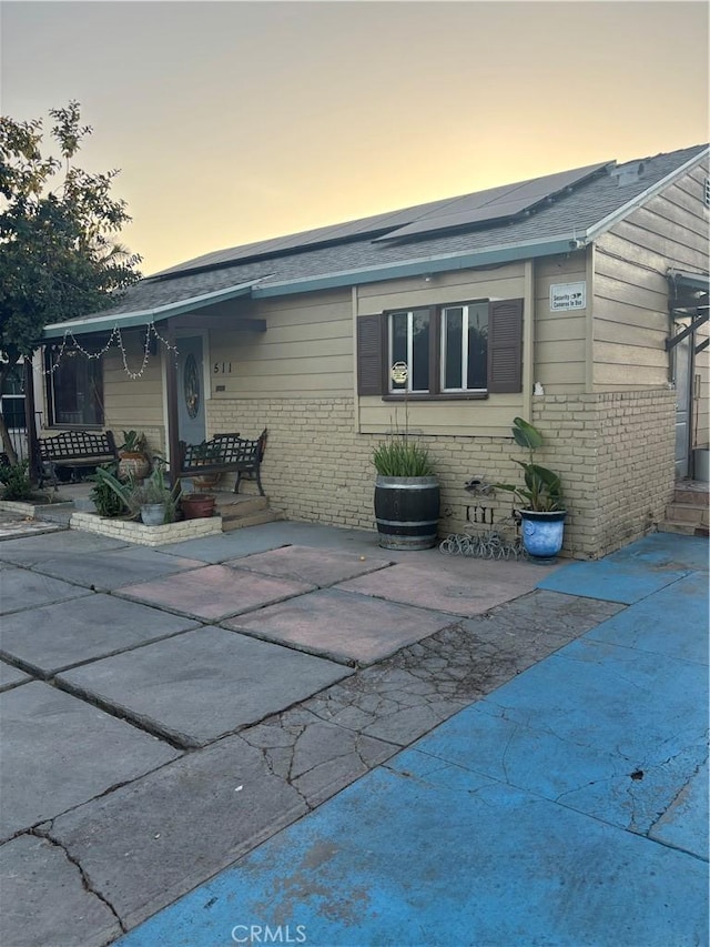 back house at dusk featuring a patio