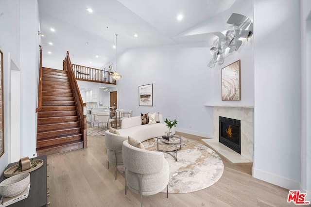 living room featuring high vaulted ceiling, light hardwood / wood-style flooring, and a premium fireplace