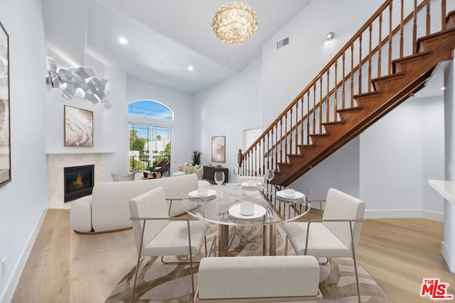 dining room featuring light hardwood / wood-style floors, a chandelier, lofted ceiling, and a premium fireplace