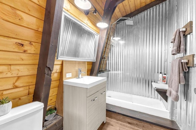 bathroom featuring hardwood / wood-style flooring, wooden walls, vanity, and toilet