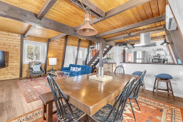 dining room with wood ceiling, beam ceiling, wooden walls, and light hardwood / wood-style floors