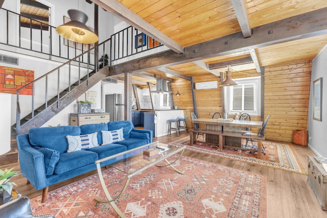 living room featuring wood ceiling, wooden walls, beam ceiling, and light wood-type flooring