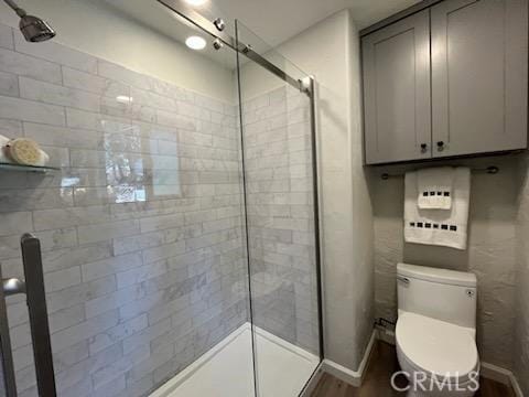 bathroom featuring wood-type flooring, toilet, and an enclosed shower