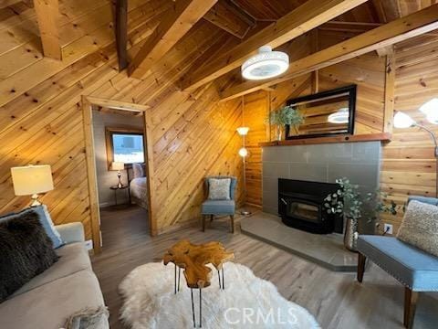 living room with hardwood / wood-style flooring, a wood stove, and wooden walls