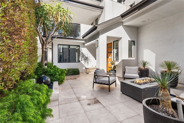 view of patio with a balcony and an outdoor fire pit