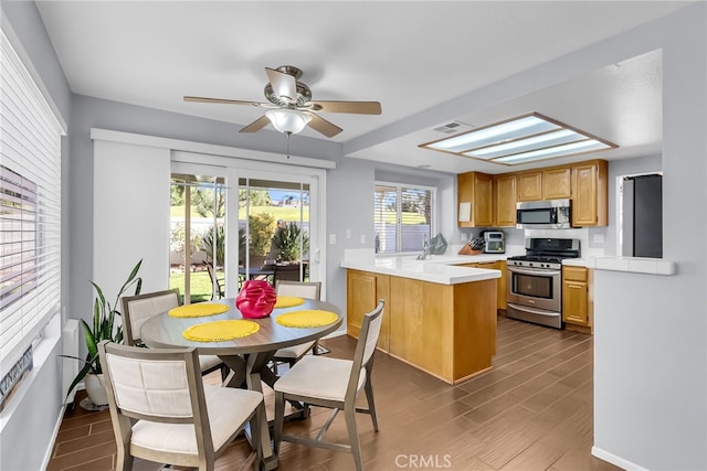 kitchen featuring a skylight, ceiling fan, dark hardwood / wood-style flooring, kitchen peninsula, and appliances with stainless steel finishes