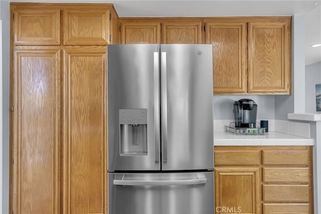 kitchen with stainless steel refrigerator with ice dispenser and tile countertops