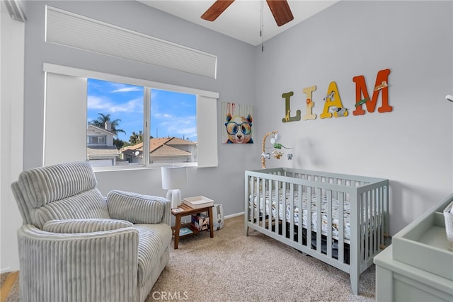 carpeted bedroom with ceiling fan and a crib