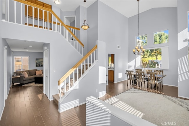 staircase featuring a chandelier, wood-type flooring, and high vaulted ceiling