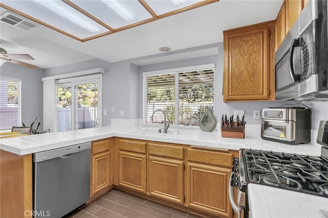 kitchen with kitchen peninsula, tile counters, stainless steel appliances, and sink