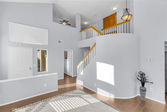 foyer entrance with ceiling fan, dark hardwood / wood-style floors, and a high ceiling