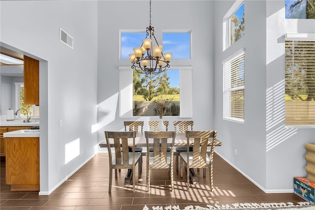 dining space featuring sink, dark hardwood / wood-style flooring, a towering ceiling, and an inviting chandelier