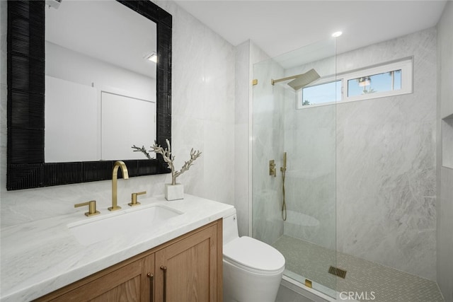 bathroom with tiled shower, vanity, and toilet