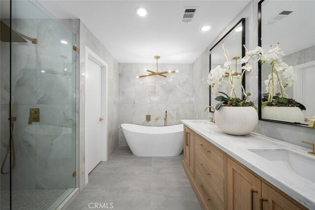 bathroom featuring tile walls, vanity, and separate shower and tub