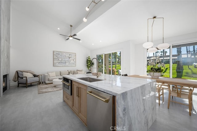 kitchen featuring appliances with stainless steel finishes, pendant lighting, sink, a kitchen island with sink, and light stone counters