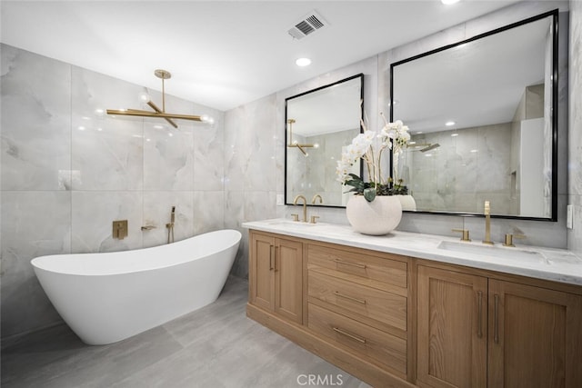 bathroom with an inviting chandelier, vaulted ceiling, tile walls, vanity, and independent shower and bath