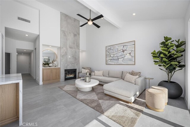 living room featuring a tiled fireplace, ceiling fan, high vaulted ceiling, and beamed ceiling