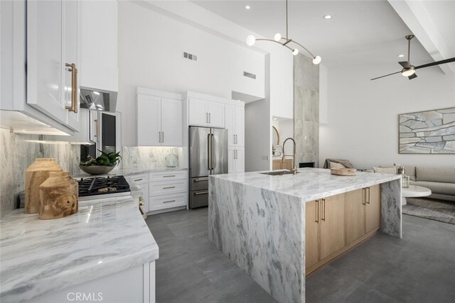 kitchen featuring white cabinetry, light stone countertops, high quality fridge, and sink