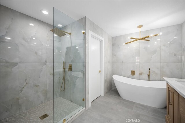 bathroom featuring vanity, separate shower and tub, tile walls, and a notable chandelier