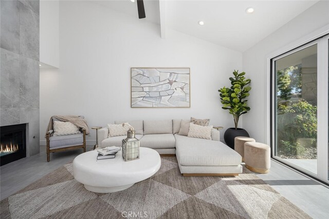 living room with a tiled fireplace and vaulted ceiling with beams