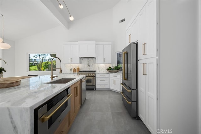 kitchen featuring high end appliances, sink, white cabinets, and light stone counters