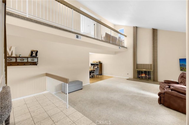 carpeted living room with a towering ceiling and a brick fireplace