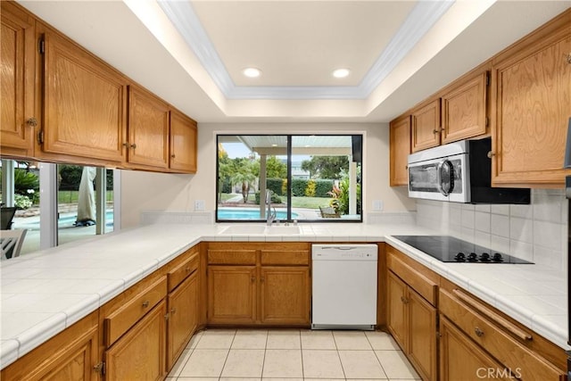 kitchen featuring white dishwasher, tile counters, black electric cooktop, and light tile patterned floors