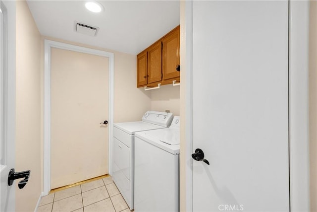 laundry room featuring cabinets, light tile patterned flooring, and washing machine and dryer