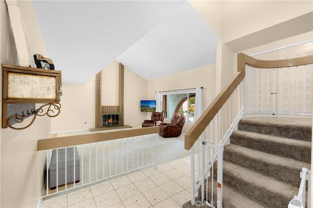 stairway featuring tile patterned floors, vaulted ceiling, and a brick fireplace