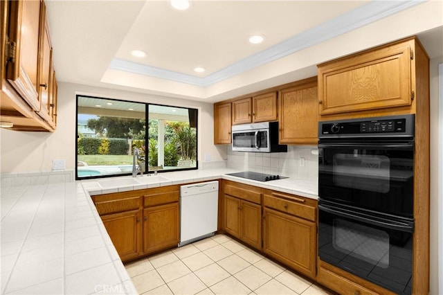 kitchen featuring decorative backsplash, sink, black appliances, light tile patterned floors, and tile countertops