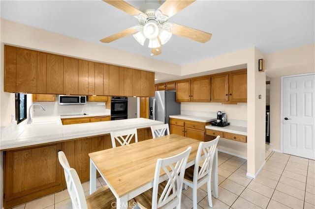 kitchen with kitchen peninsula, appliances with stainless steel finishes, ceiling fan, sink, and light tile patterned floors