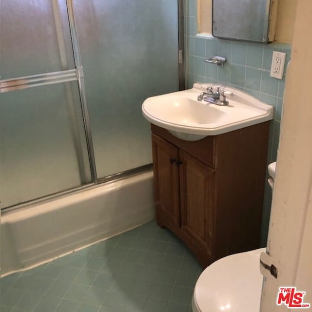 full bathroom featuring backsplash, tile patterned floors, bath / shower combo with glass door, toilet, and vanity