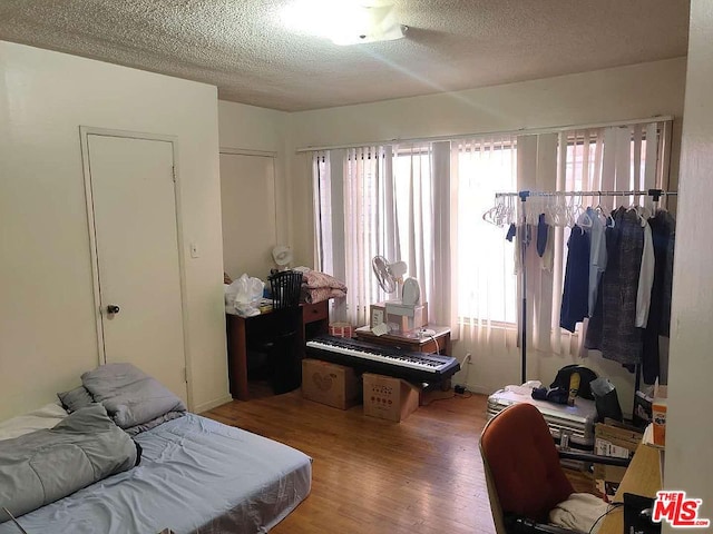 bedroom with hardwood / wood-style floors, a textured ceiling, and multiple windows