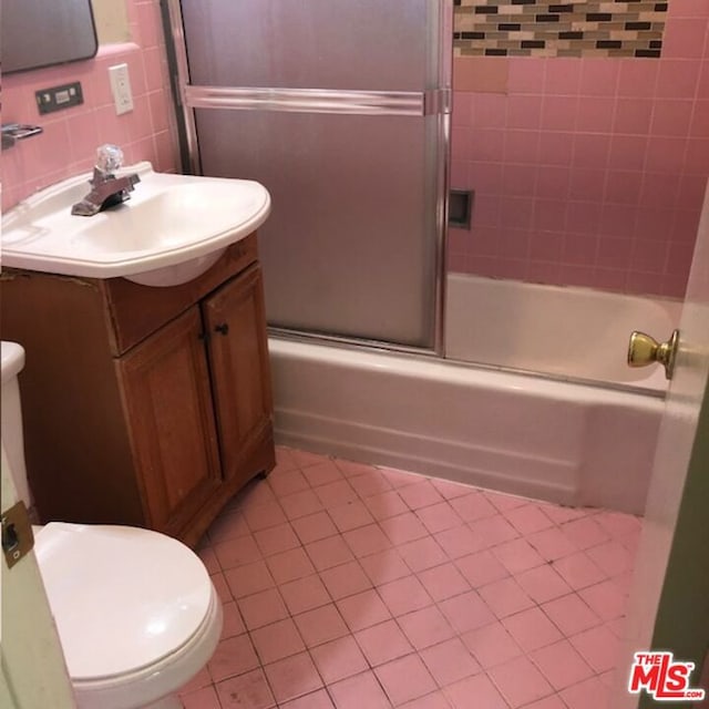 full bathroom featuring backsplash, bath / shower combo with glass door, toilet, vanity, and tile walls