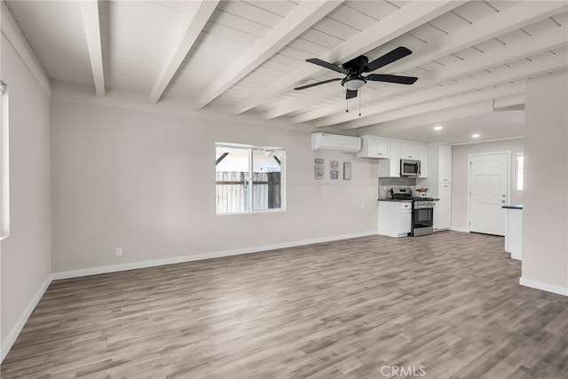 unfurnished living room with a wall unit AC, ceiling fan, light hardwood / wood-style floors, and beam ceiling