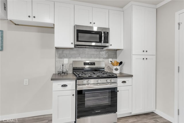 kitchen with backsplash, white cabinets, light wood-type flooring, and stainless steel appliances