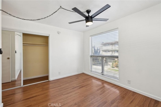 unfurnished bedroom featuring ceiling fan, a closet, wood finished floors, and baseboards